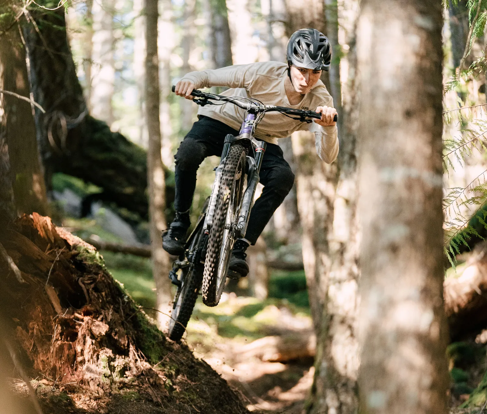 Mountainbiker springt over een boomwortel op een bospad